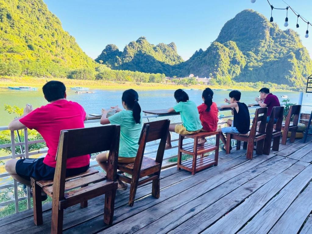 eine Gruppe von Menschen, die an einem Tisch auf einem Dock sitzen in der Unterkunft Phong Nha Coco House in Phong Nha