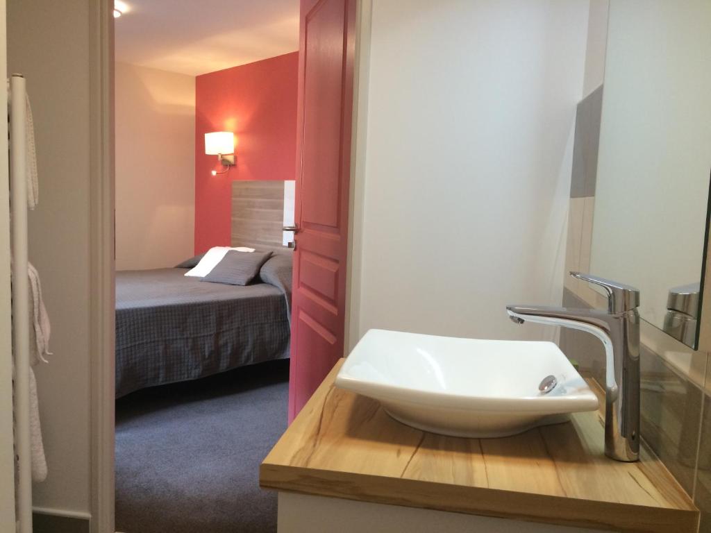 łazienka z umywalką oraz pokój z łóżkiem w obiekcie Auberge du Cheval Blanc Logis w mieście Chamouilley