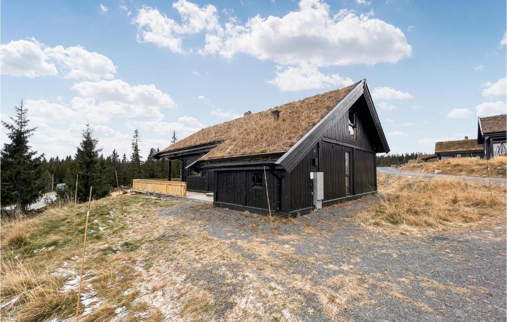 a black barn sitting on top of a field at Cozy Home In Sjusjen With Kitchen in Sjusjøen