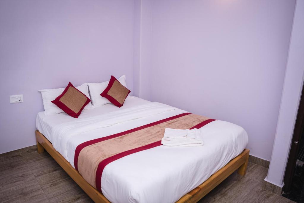 una camera da letto con un letto con lenzuola bianche e cuscini rossi di Hotel sunrise heaven a Pokhara
