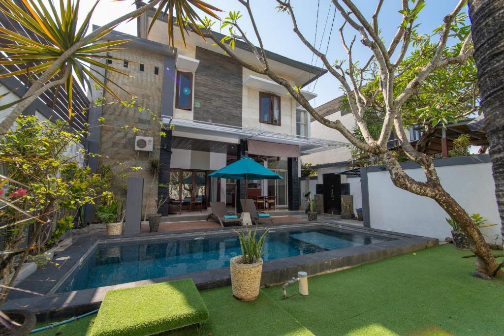 a backyard with a swimming pool and a house at Villa Taurus in Seminyak