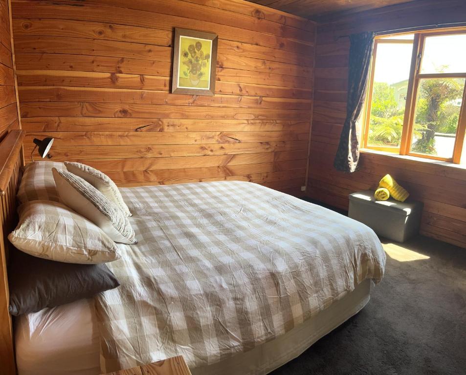 1 dormitorio con 1 cama y pared de madera en Classic Kiwi bach en Granity