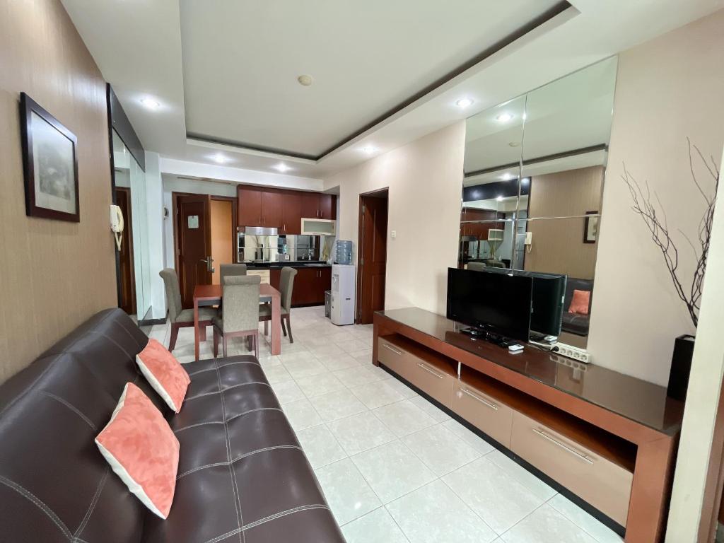 ein Wohnzimmer mit einem Sofa und einem TV in der Unterkunft Super Studio Galeri Ciumbuleuit 1 (1BR, 1BA, Kitchen) in Bandung