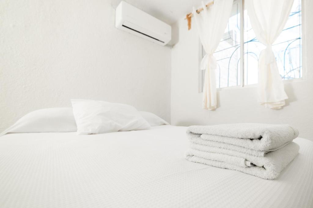 um quarto branco com uma cama branca com toalhas em Casa Leon Rinconada em Puerto Escondido
