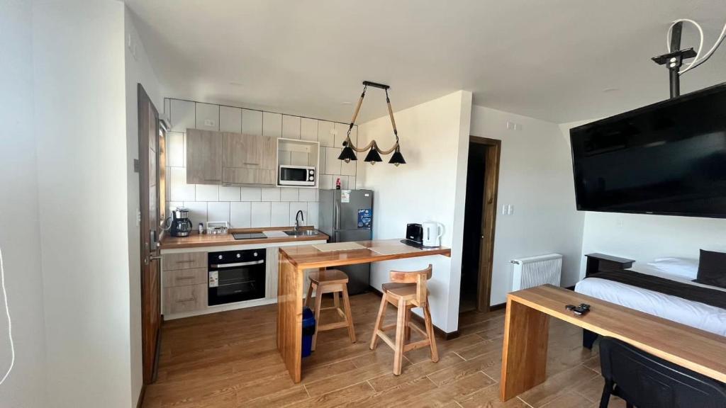 a small kitchen with a desk and a bed in a room at Origenes Apartments in Puerto Natales