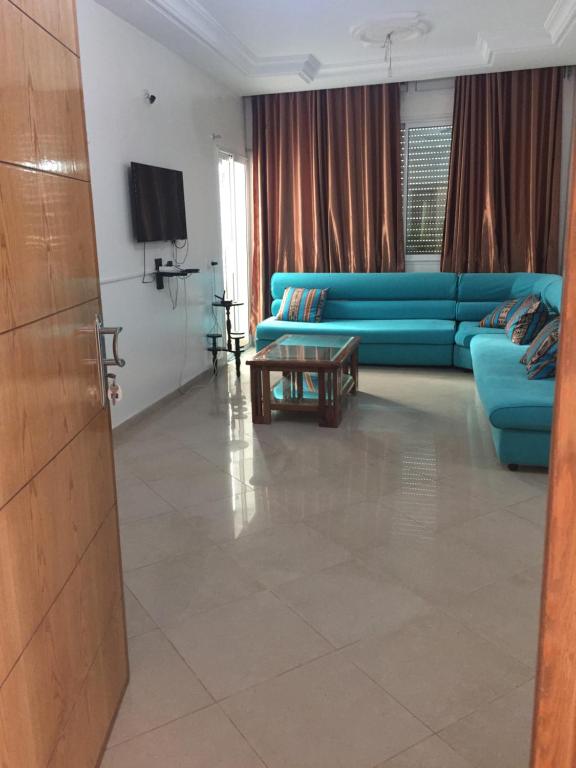 sala de estar con sofá azul y mesa en un nouveau appartement avec un parking gratuit sur place en La Marsa
