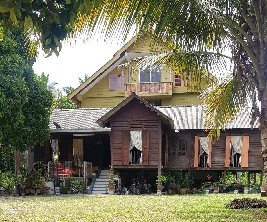 Batu Kikir的住宿－Roomstay "Ghumah Uwan"，前面有棕榈树的房子