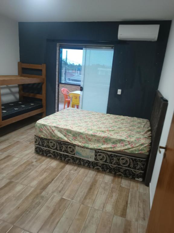 een slaapkamer met een bed en een houten vloer bij Apartamento completo praia do sonho in Palhoça