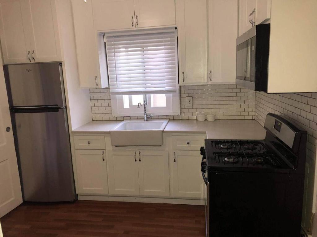 uma cozinha com armários brancos, um lavatório e um frigorífico em Skyline Siesta: Chic Couch Quarters in Heart of Echo Park – DTLA Awaits em Los Angeles