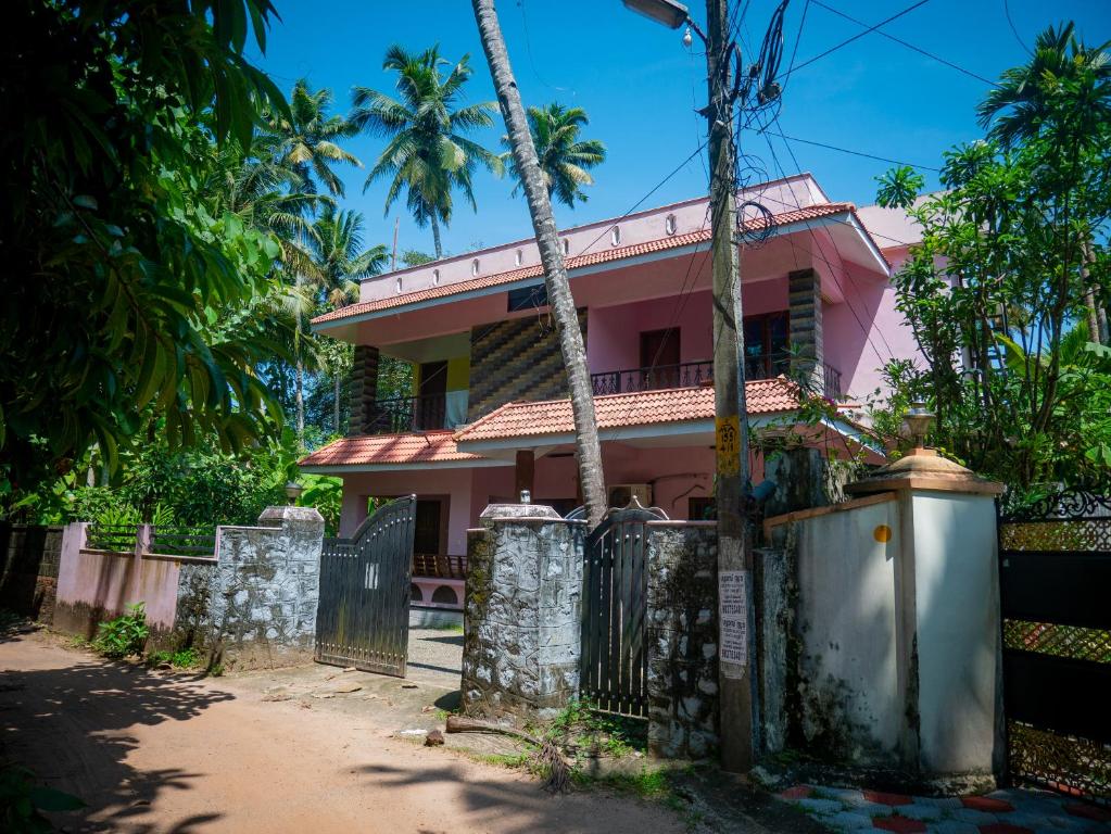 uma casa cor-de-rosa com uma vedação à frente. em Body Manthra em Varkala
