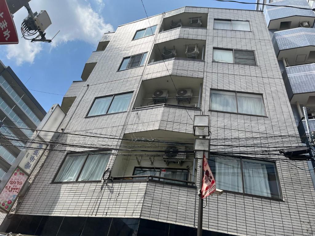 a tall gray building with windows and a flag at 小団体大関係 in Toda