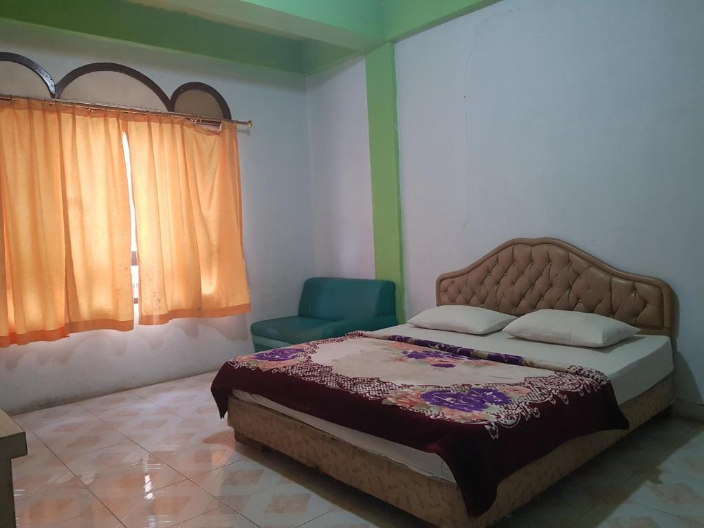 a bedroom with a bed and a chair and a window at OYO 93237 Hotel Triarga in Takengon