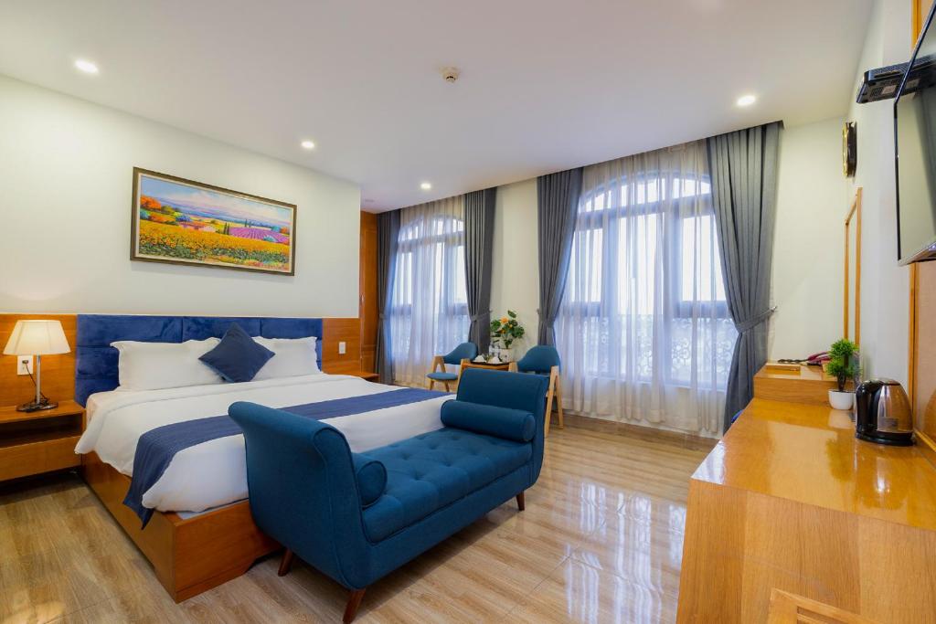 een slaapkamer met een groot bed en een blauwe stoel bij Vivian Airport Hotel Saigon in Ho Chi Minh-stad