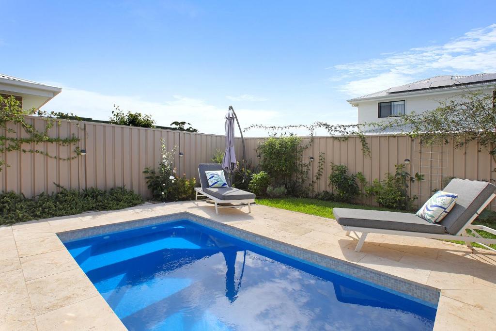 a swimming pool in a backyard with two chairs next to it at Waiheke Marina Getaway in Shellharbour