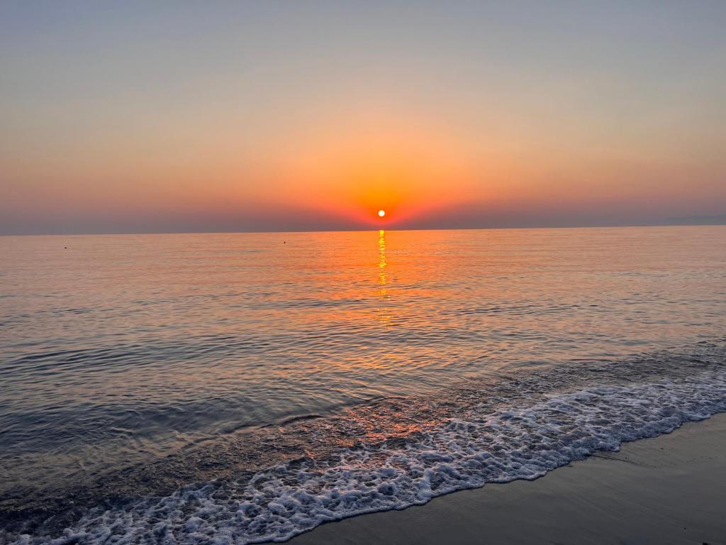 einen Sonnenuntergang über dem Meer mit Sandstrand in der Unterkunft Parco La Bruca Villetta Margherita 800 mt dal mare in Cipollina