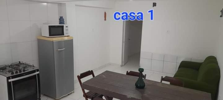 een keuken met een tafel, een fornuis en een magnetron bij Areia Branca / Casa 1/ casa 2 in Cabo Frio