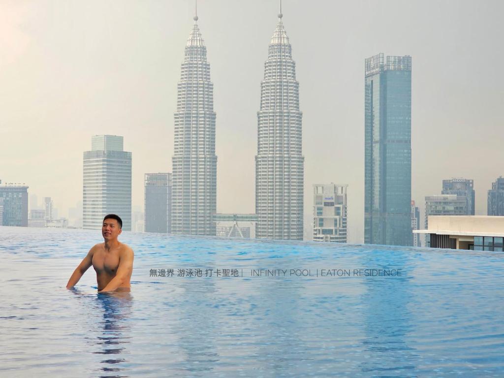 吉隆坡Eaton Residence KLCC View with Infinity Pool 伊顿公寓 豪景园 双子塔无边际泳池的在一个城市的无边游泳池里,一个人