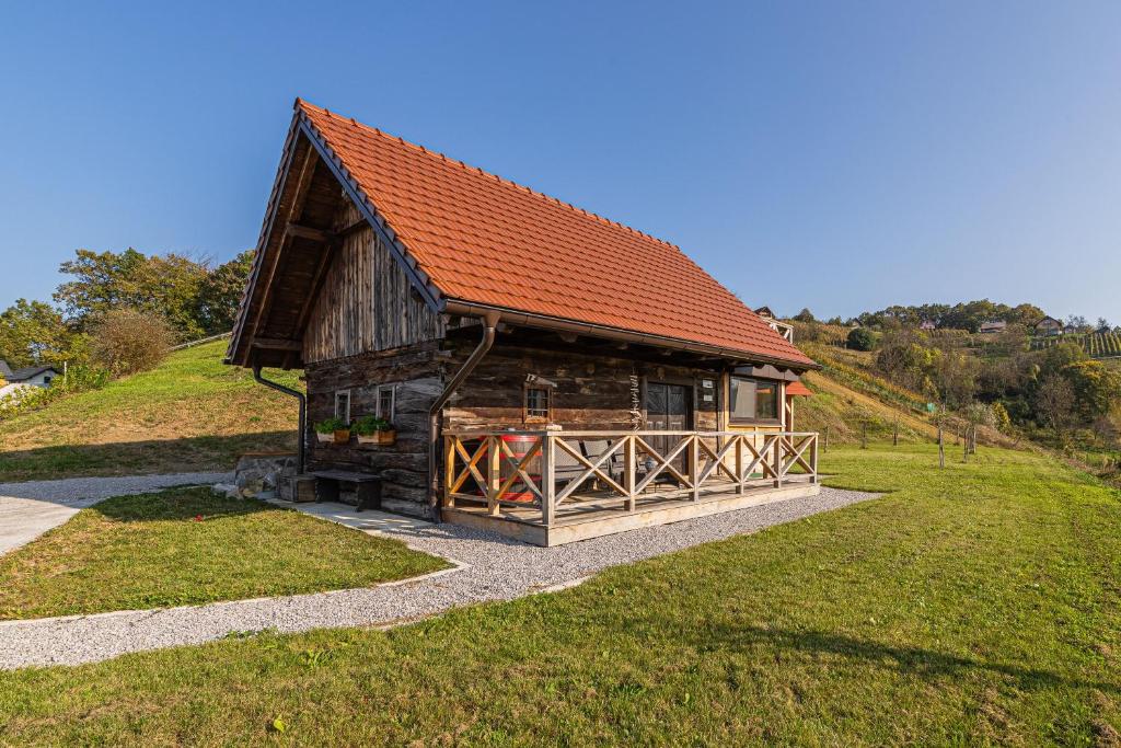 una baita di tronchi con tetto rosso su una collina di Vineyard Cottage Grajska Kašča - Happy Rentals a Mirna