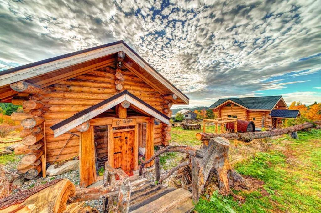 uma cabana de madeira num campo com uma vedação em ECO HOUSES ART OF LIVING - Еко къщи изкуството да живееш em Pamporovo