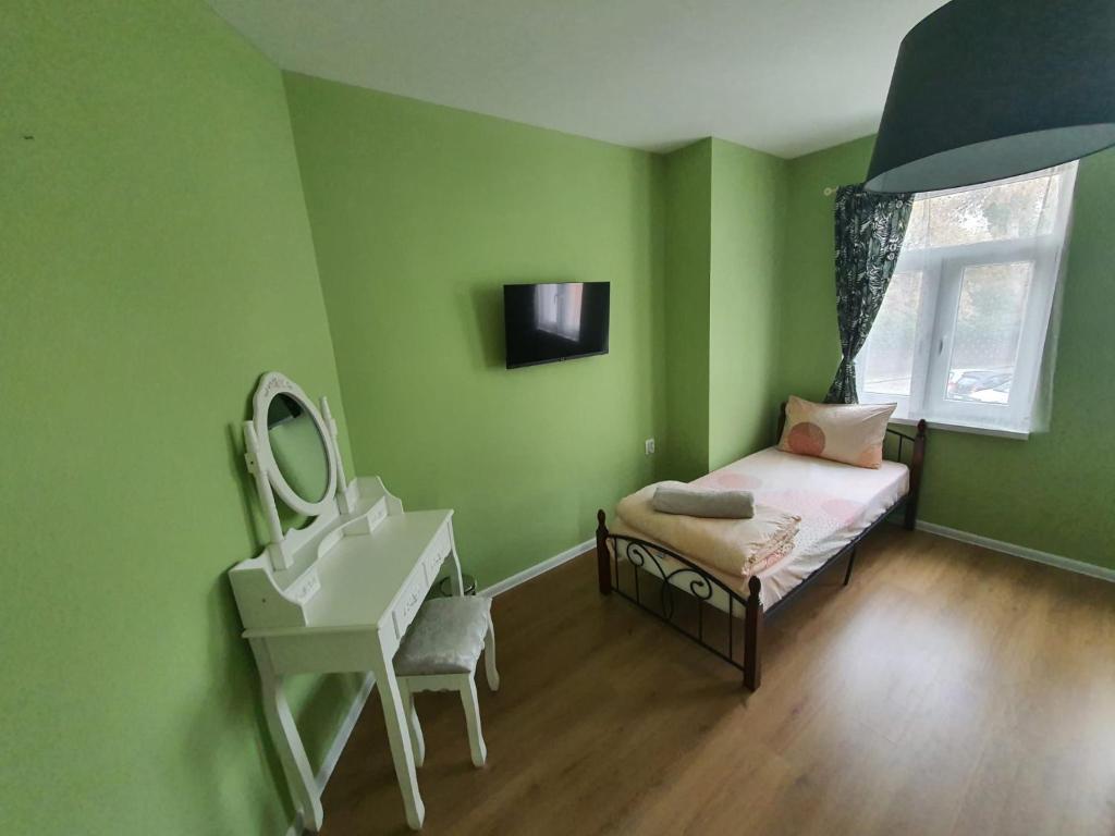 een groene kamer met een bed, een wastafel en een spiegel bij HANCHO - OLD TOWN CENTER PLOVDIV in Plovdiv
