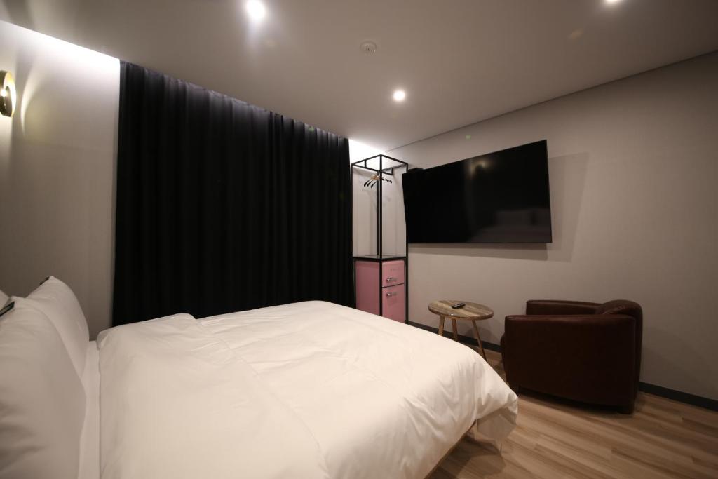 a bedroom with a white bed and a television at Stay Oneul in Gongju