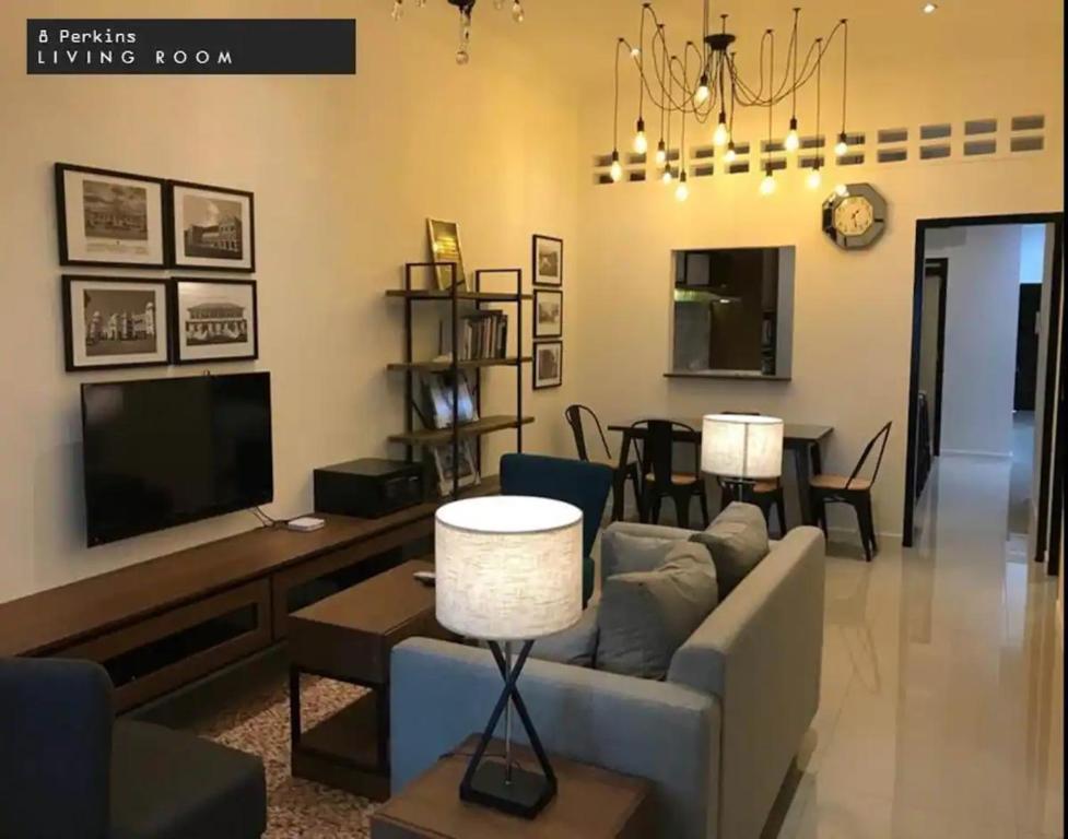 uma sala de estar com um sofá e uma televisão em IPOH 8Perkins Canning Garden 7-8pax Elegant Homestay with 4Bedrooms, 3Bathroom, 1Living, 1Dining, 1Kitchen-Bar with 3Parkings em Ipoh