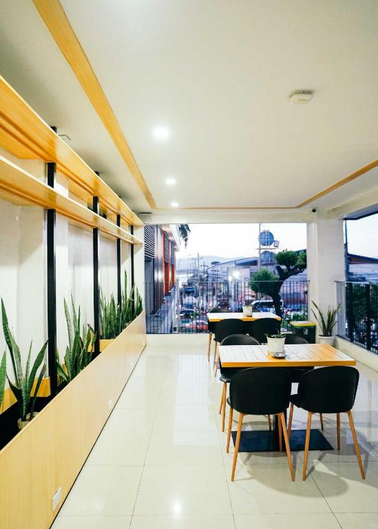 a restaurant with tables and chairs and a large window at Travelbee Airport Inn in Mactan