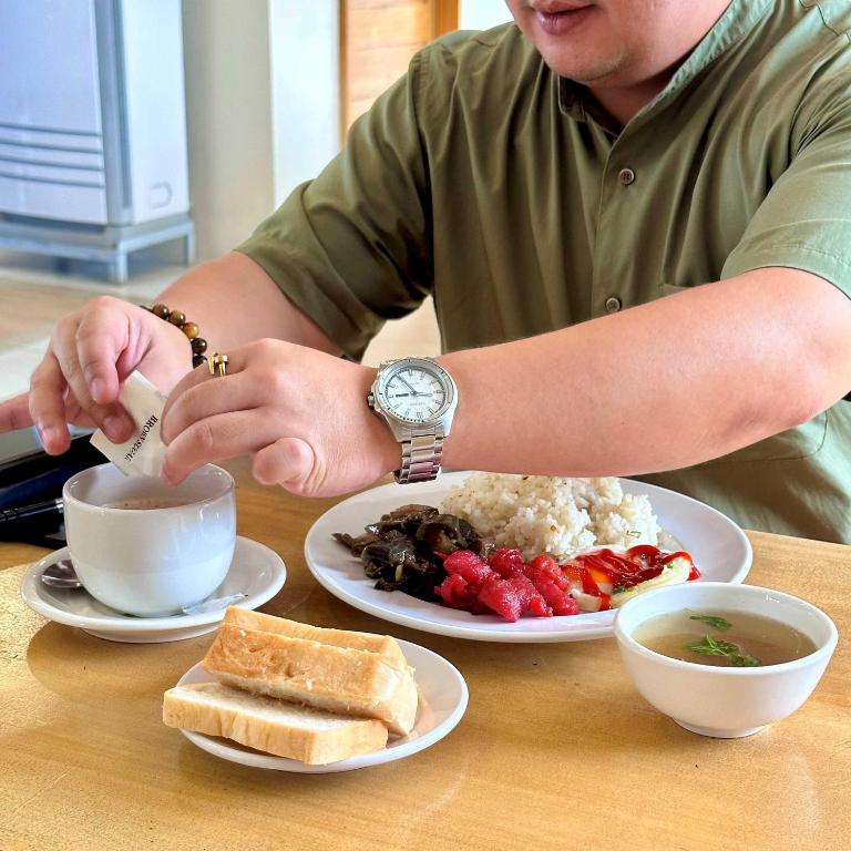 a man sitting at a table with a plate of food at Travelbee Airport Inn in Mactan