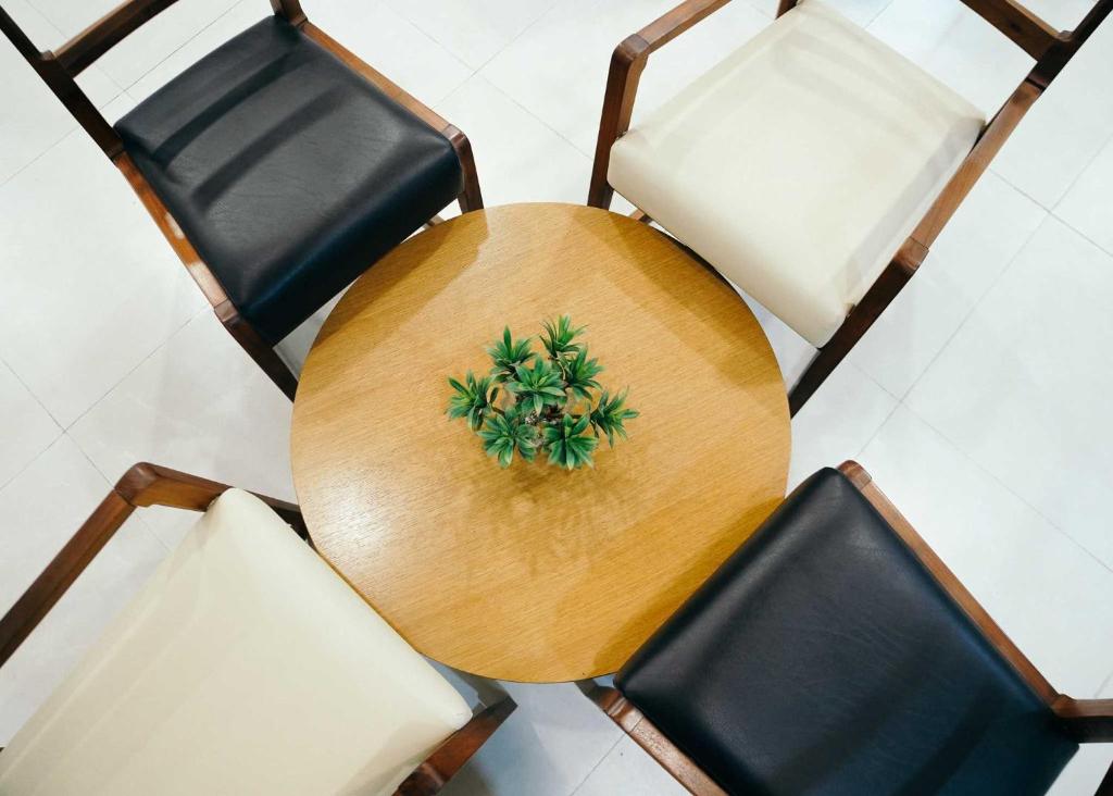 a wooden table and four chairs with a plant on it at Travelbee Airport Inn in Mactan