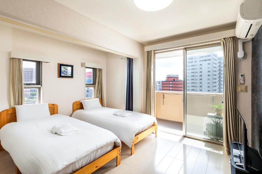 2 Betten in einem Zimmer mit einem großen Fenster in der Unterkunft Tenjin Minami San Ban Kan in Fukuoka