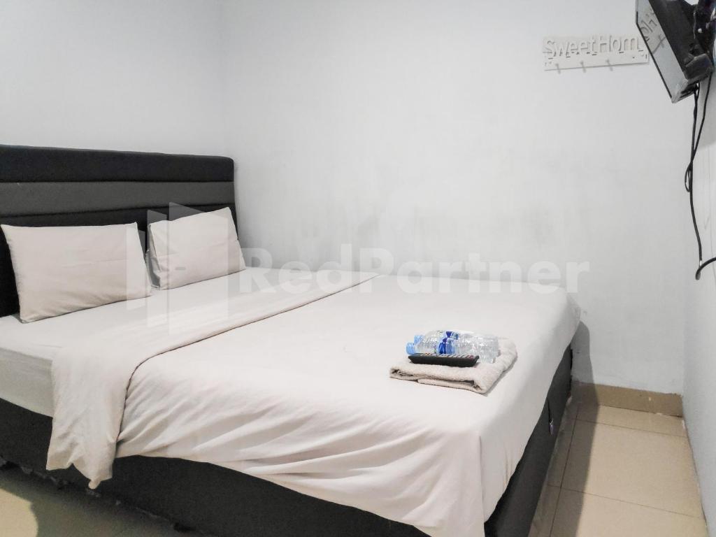 Un dormitorio con una cama con sábanas blancas y almohadas blancas. en Ada Guest House Medan Redpartner, en Medan
