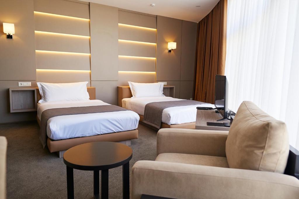 um quarto de hotel com duas camas e um sofá em City Stay Bishkek em Bishkek