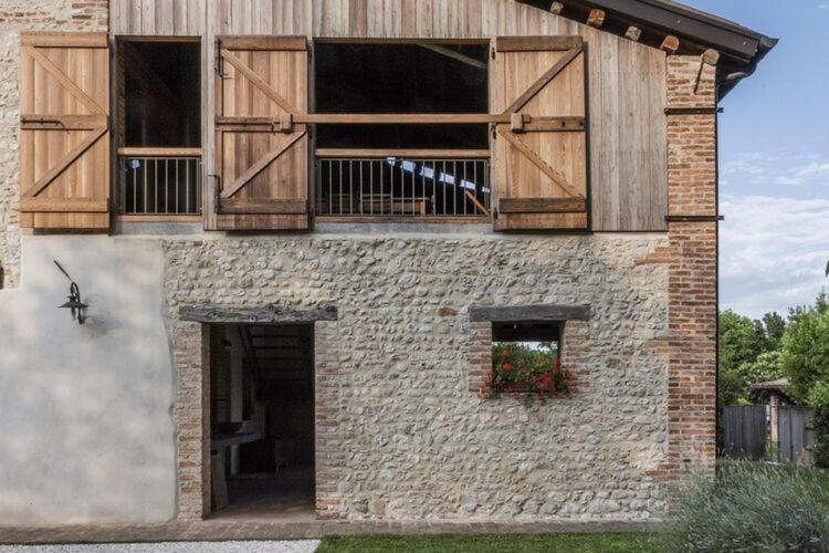 a brick building with wooden doors and a window at Modern Farmhouse in Pagnano Italy near Forest in Asolo