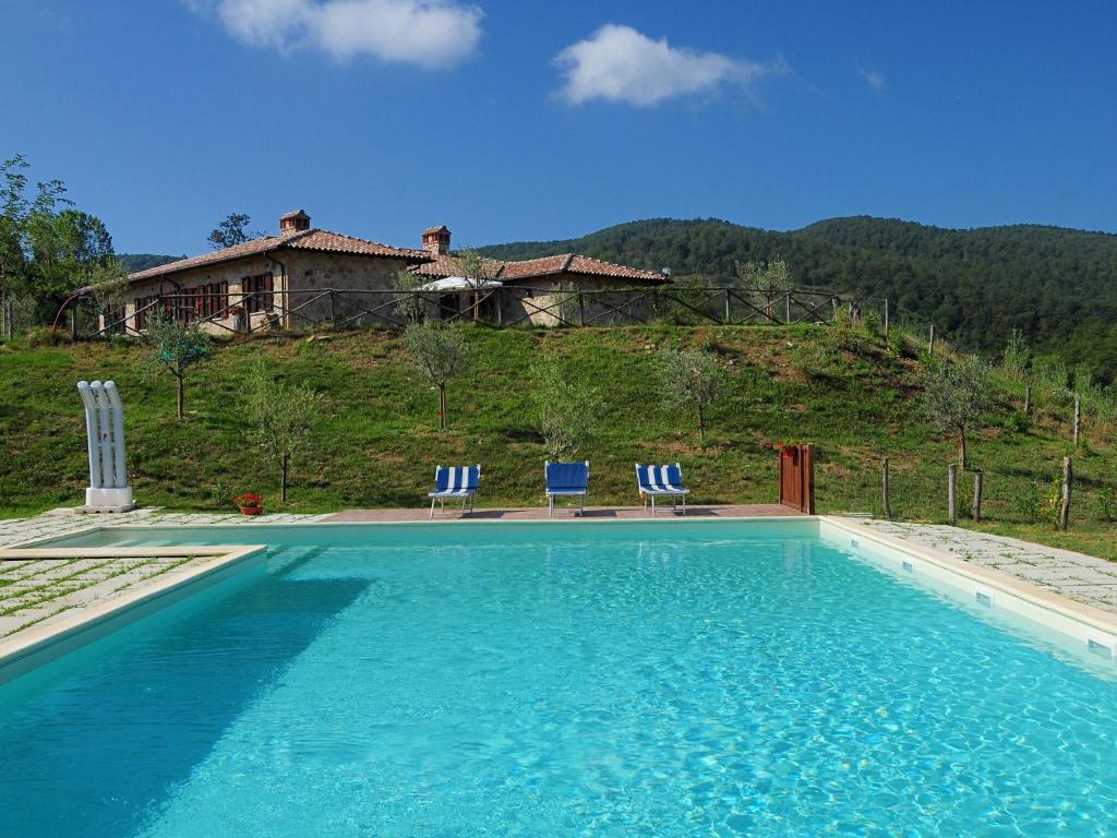 a swimming pool with chairs and a house in the background at Stunning Farmhouse in Passignano with Pool in Passignano sul Trasimeno