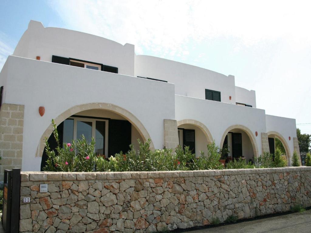 a white house with a stone wall in front of it at Holiday home 400 meters from the sea near Gallipoli in Nardò