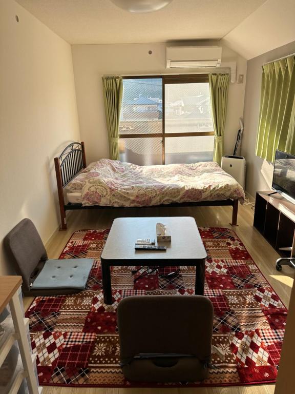 鹿児島市にある短期賃貸ビッグバーンズマンション田上のベッドルーム1室(ベッド1台、テーブル、ラグ付)