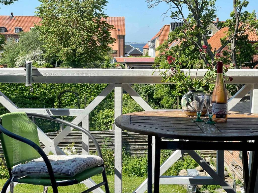 a wooden table with a bottle of wine on a balcony at Charmerende Lejlighed I Stege Midtby in Stege