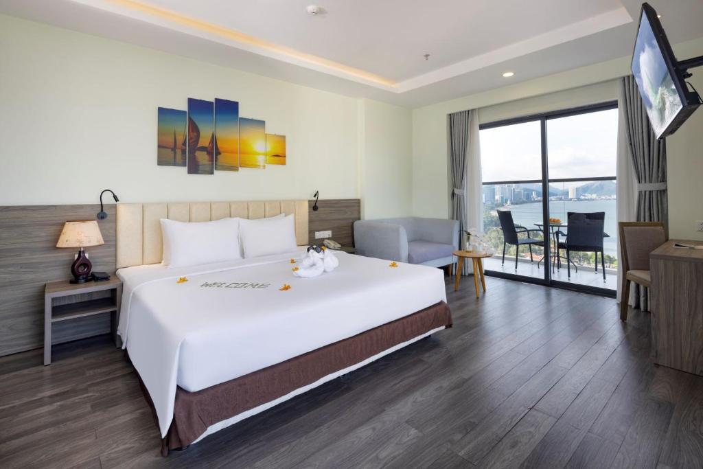 Un dormitorio con una gran cama blanca y un balcón. en Xavia Hotel, en Nha Trang
