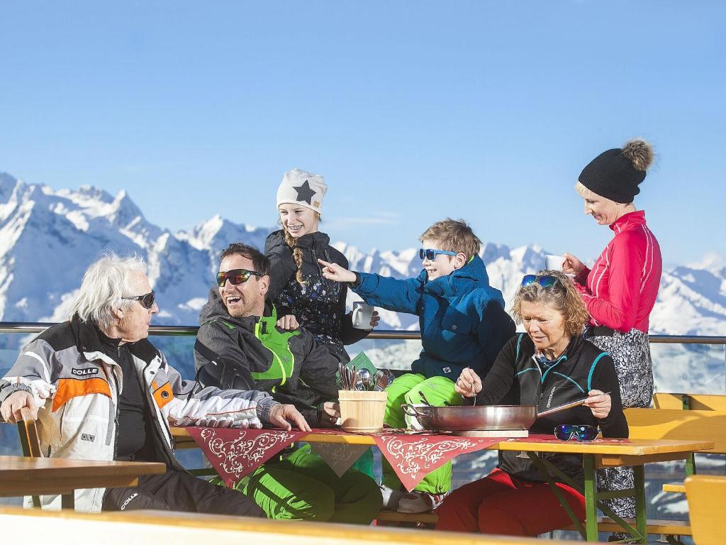 a group of people sitting at a table with mountains in the background at Apartment in Bramberg am Wildkogel with balcony in Bramberg am Wildkogel