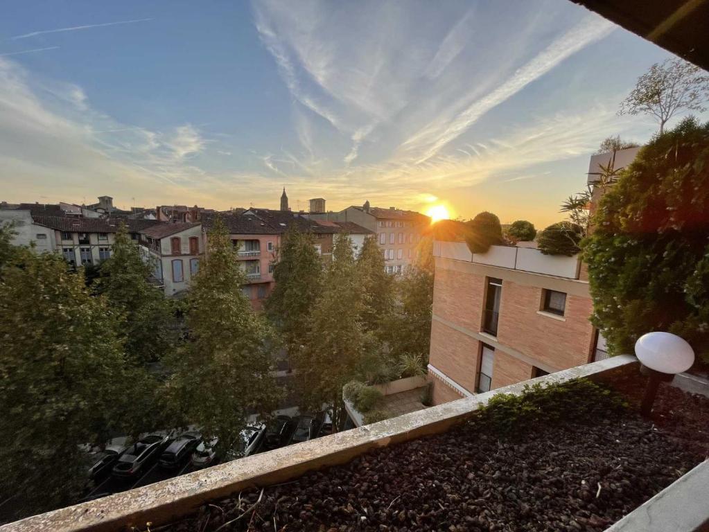 uma vista para o pôr-do-sol a partir da varanda de um edifício em Charlie et la Chocolaterie- Parking- Clim- CentreVille em Montauban