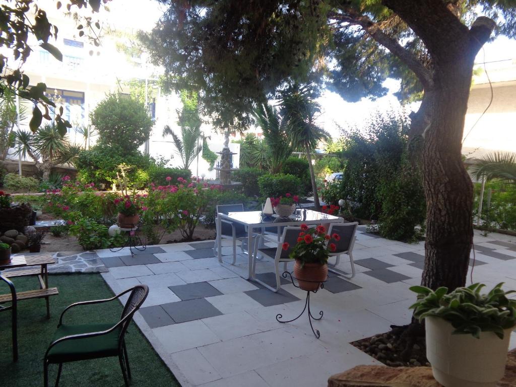 un patio con mesa, sillas y un árbol en Angela Hotel en Agia Marina Aegina