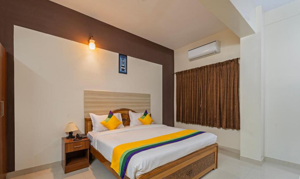 Schlafzimmer mit einem Kingsize-Bett und bunten Kissen in der Unterkunft Itsy By Treebo - Sri Mani'S Residency, Coimbatore Airport in Coimbatore