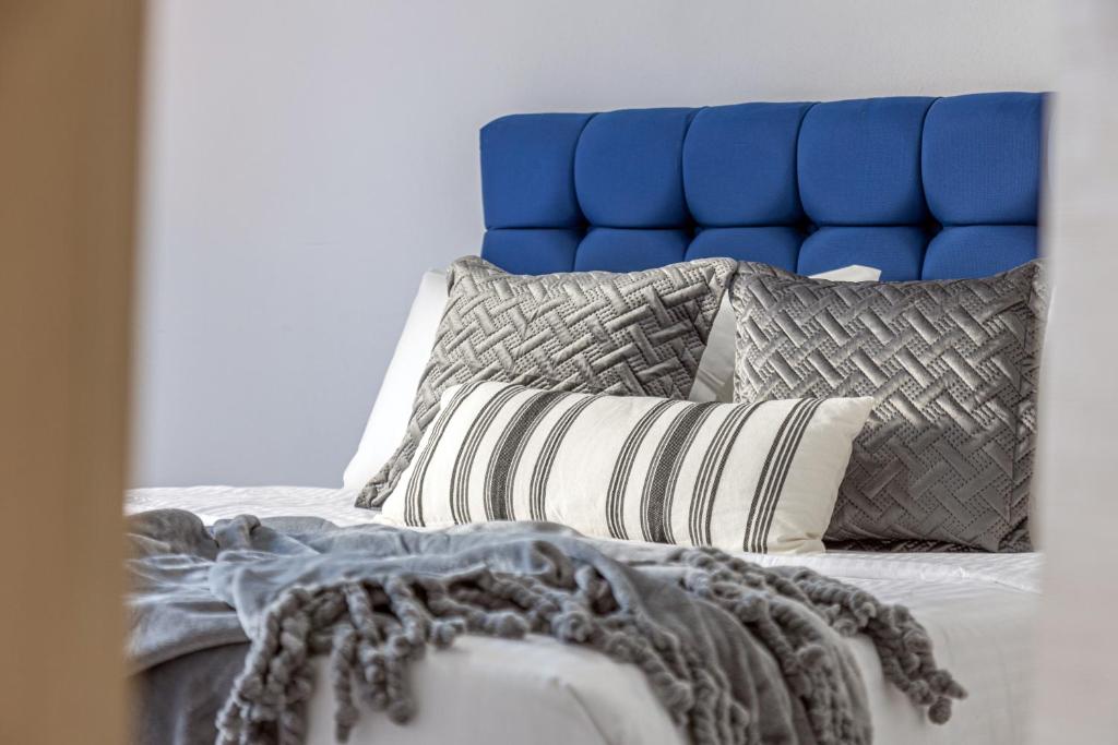 a bed with a blue head board and pillows at Kappa Apartment in Heraklio