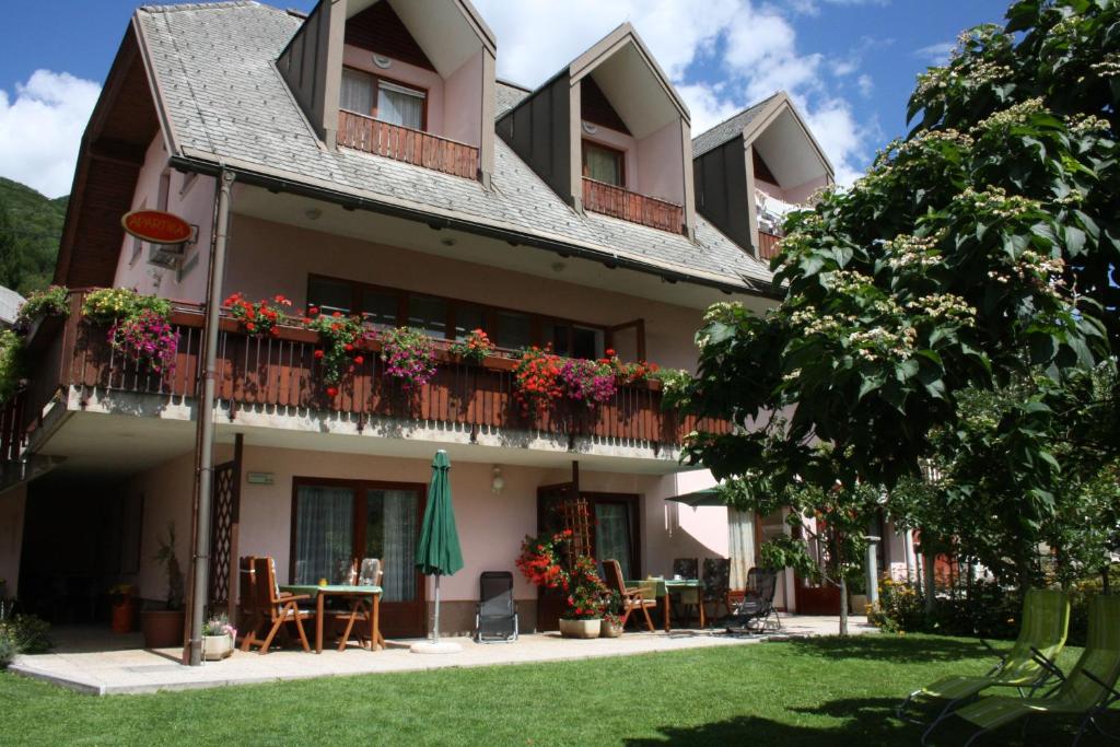 ein Gebäude mit Blumen auf den Balkonen und einem Tisch in der Unterkunft Apartments Kravanja in Bovec