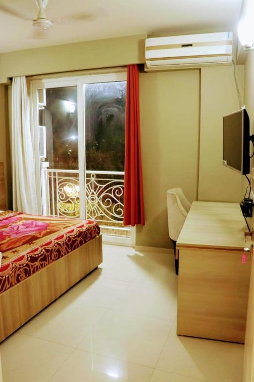 a bedroom with a bed and a window and a desk at Sridham Holiday Vrindavan in Vrindāvan
