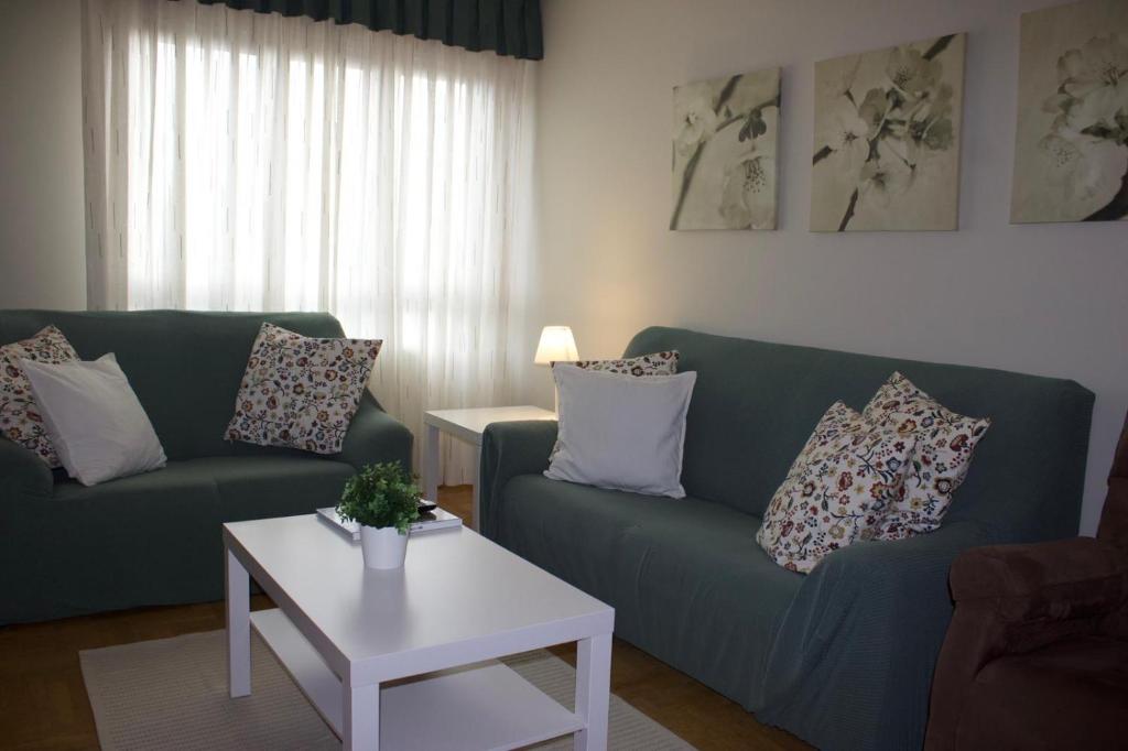 a living room with a green couch and a table at Apartamento Cueto in Soto del Barco
