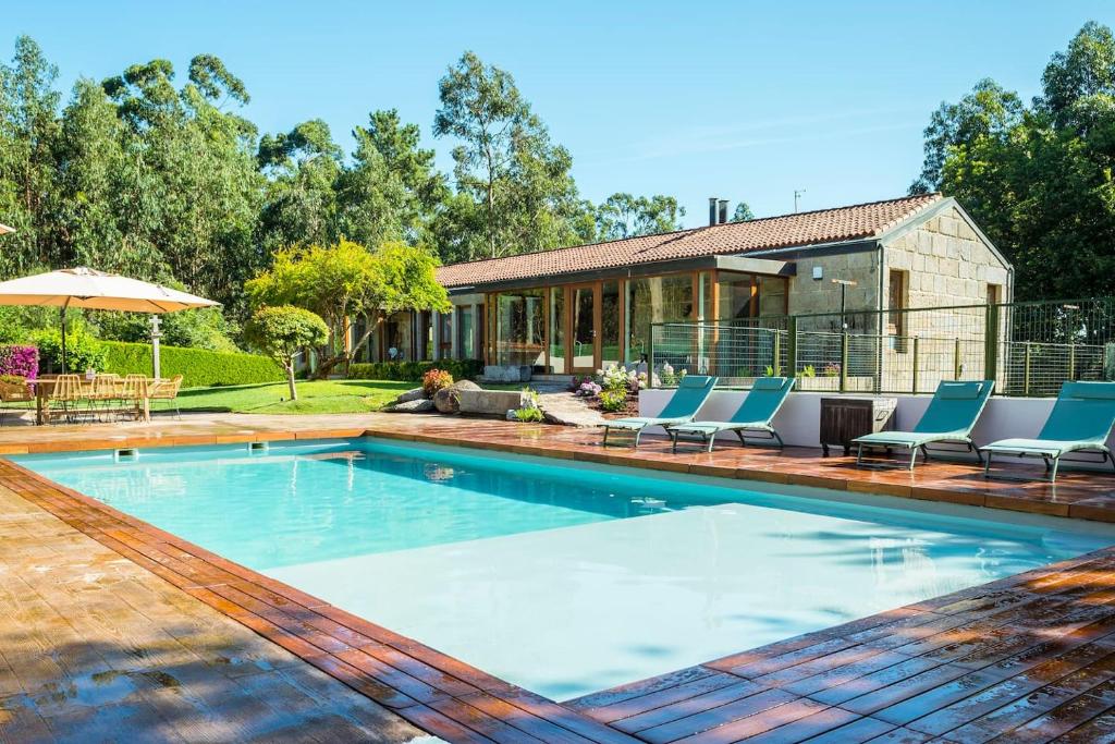 a swimming pool with chairs and a house at La Panera de Pucho in Pontevedra