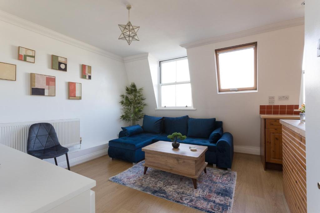 a living room with a blue couch and a table at Cosy 2-Bed Flat - Great Views of London! in London