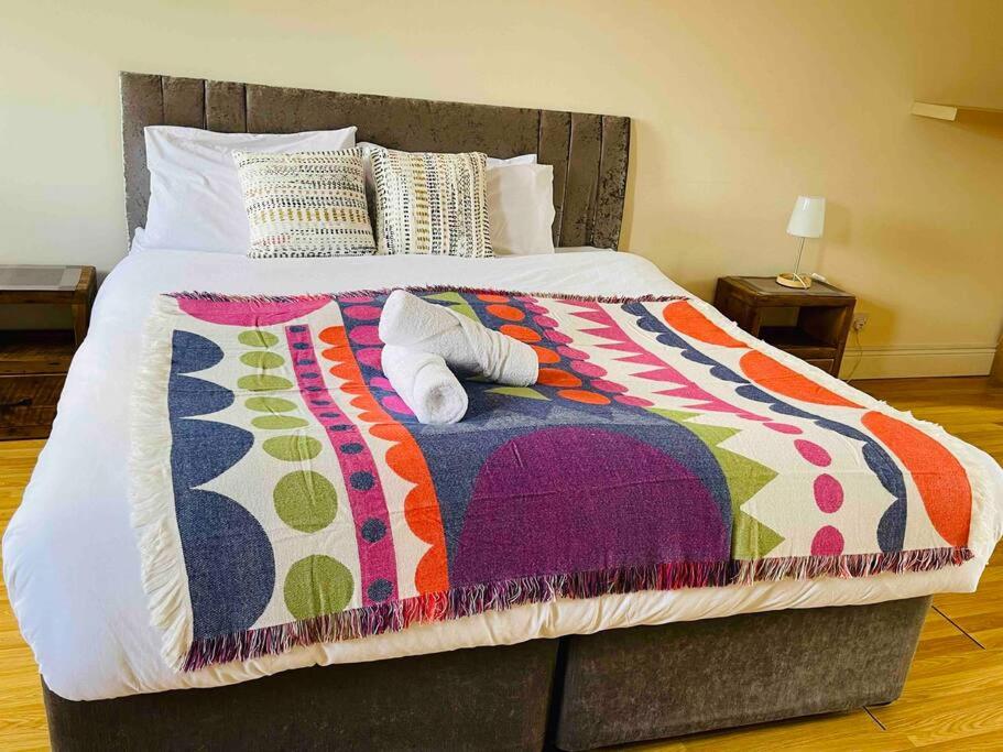 Una cama grande con una manta colorida. en Check our discount Executive 3 bed house en St Ives