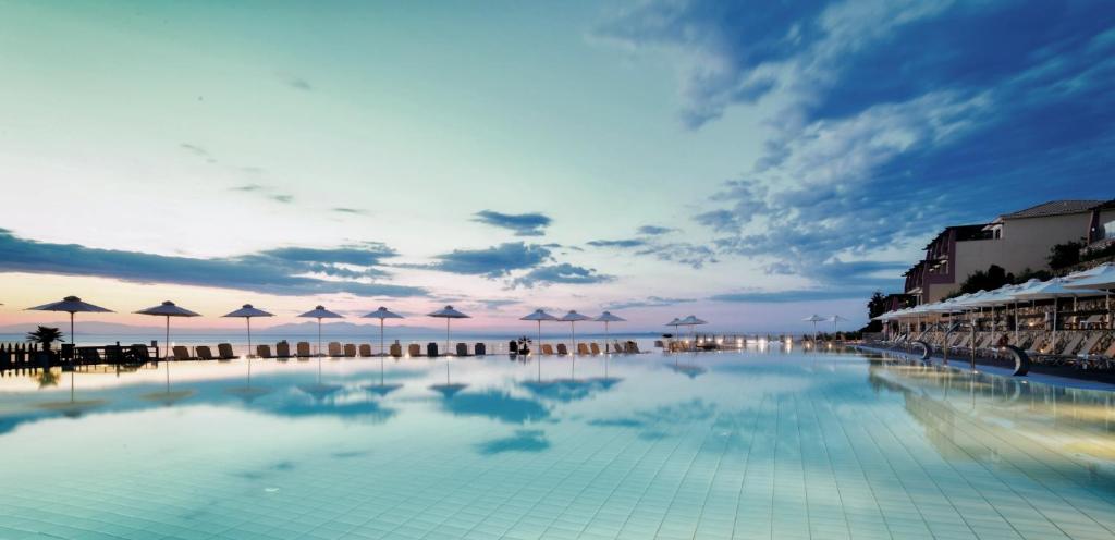 una gran piscina con sombrillas en una playa en Apostolata Island Resort and Spa, en Skala